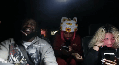 A Group Of People In A Car With One Wearing A Pink Shirt That Says Ink GIF
