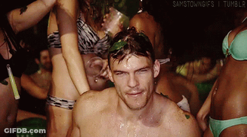 A Group Of People In Bikinis Are Gathered Around A Man With A Green Leaf On His Head .. GIF