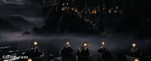A Group Of People In Boats With Lanterns In The Water In Front Of A Castle GIF