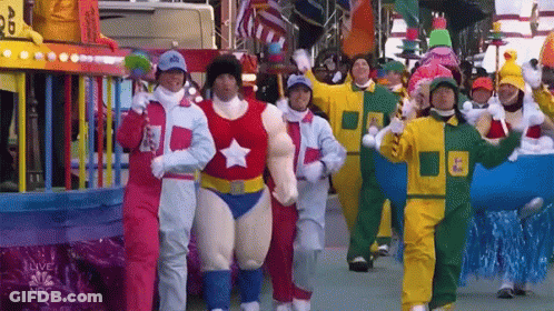 A Group Of People In Costumes Are Walking In A Parade With The Nbc Logo On The Bottom GIF