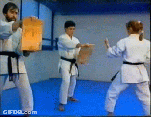 A Group Of People In Karate Uniforms Are Practicing Martial Arts In A Gym . GIF