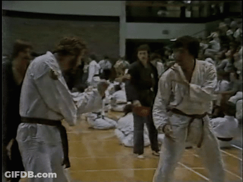 A Group Of People In Karate Uniforms Are Standing On A Court GIF
