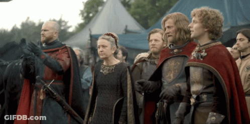 A Group Of People In Medieval Costumes Stand In Front Of A Blue Tent GIF