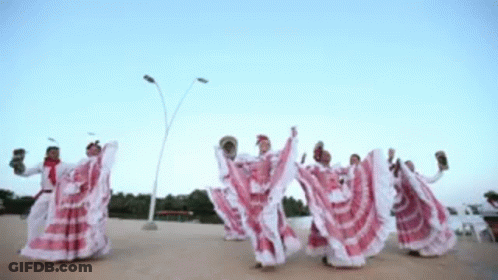 A Group Of People In Red And White Dresses Are Dancing In A Line GIF
