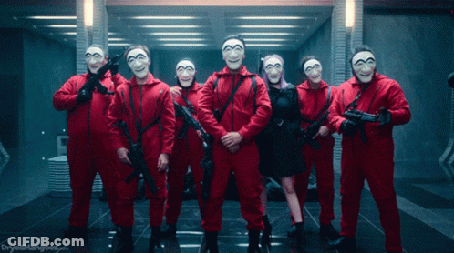 A Group Of People In Red Jumpsuits And Masks Holding Guns With The Words Dryedmangoes.com In The Corner GIF