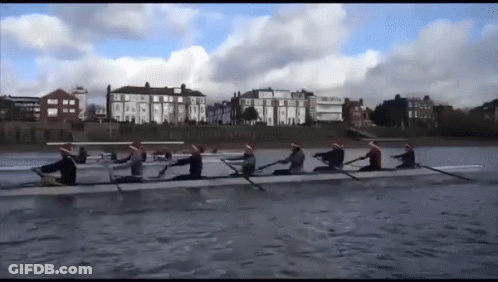 A Group Of People In Santa Hats Are Rowing On A River GIF