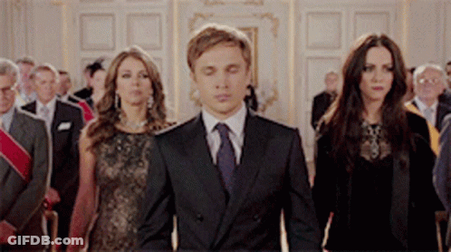 A Group Of People In Suits And Ties Are Walking In A Room GIF