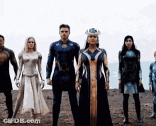 A Group Of People In Superhero Costumes Are Standing Next To Each Other In A Line . GIF