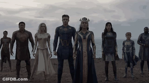 A Group Of People In Superhero Costumes Stand On A Beach GIF