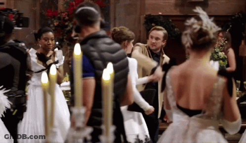 A Group Of People In White Dresses Are Standing In A Room With Candles . GIF