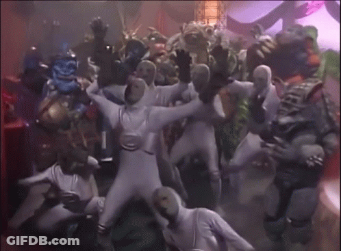 A Group Of People In White Jumpsuits Are Dancing GIF