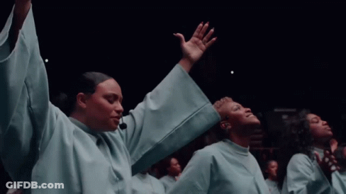 A Group Of People In White Robes Are Raising Their Hands In The Air GIF