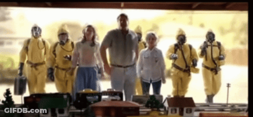 A Group Of People In Yellow Suits And Gas Masks Are Standing Next To Each Other . GIF