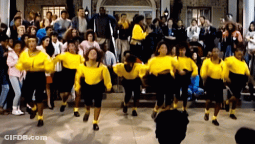 A Group Of People In Yellow Sweaters Are Dancing GIF