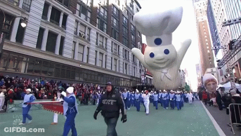 A Group Of People Marching Down A Street With A Nbc Logo In The Background GIF