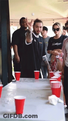 A Group Of People Playing Beer Pong With Red Cups On A Table GIF