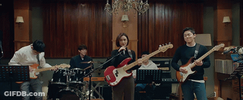 A Group Of People Playing Guitars And Singing In A Room GIF
