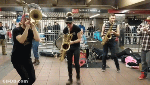 A Group Of People Playing Instruments In Front Of A Sign That Says Exit 34 St & 6Th Avenue GIF