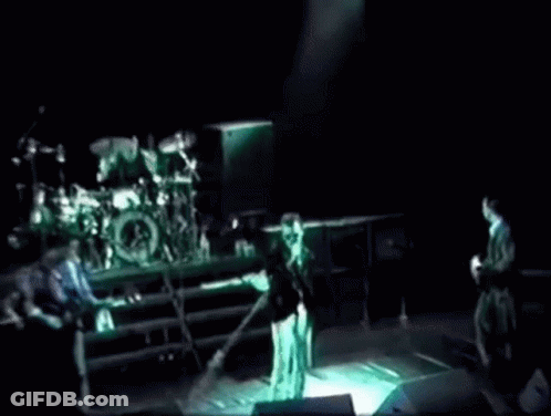A Group Of People Playing Instruments On A Stage In A Dark Room . GIF