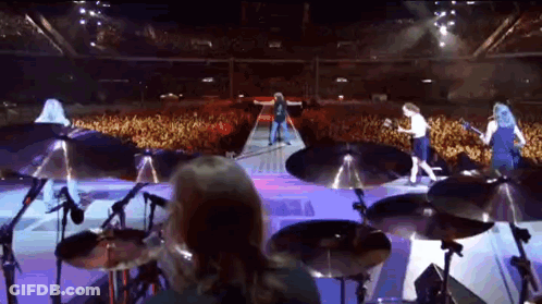 A Group Of People Playing Instruments On A Stage In Front Of A Crowd GIF