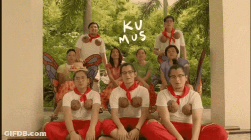 A Group Of People Posing For A Picture With The Words Ku Mus Written On The Wall Behind Them GIF
