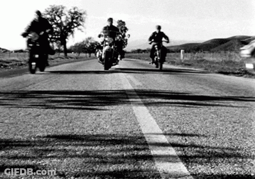 A Group Of People Riding Motorcycles Down A Road . GIF