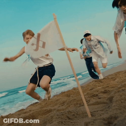 A Group Of People Running On A Beach With A Flag That Has The Letter P On It GIF