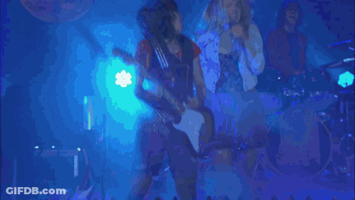 A Group Of People Singing In Front Of A Sign That Says " Determine " GIF