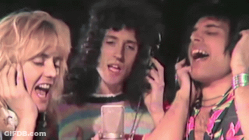 A Group Of People Singing Into A Microphone With Headphones GIF