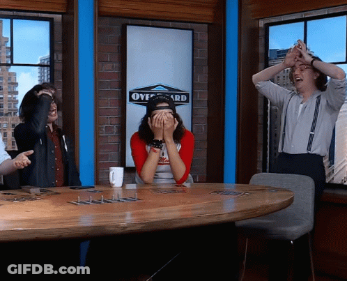 A Group Of People Sitting Around A Table With A Sign That Says Overboard On It GIF