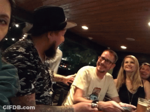 A Group Of People Sitting Around A Table With One Man Wearing A T-Shirt With A Picture Of A Dog GIF