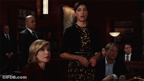 A Group Of People Sitting At A Table In A Courtroom GIF