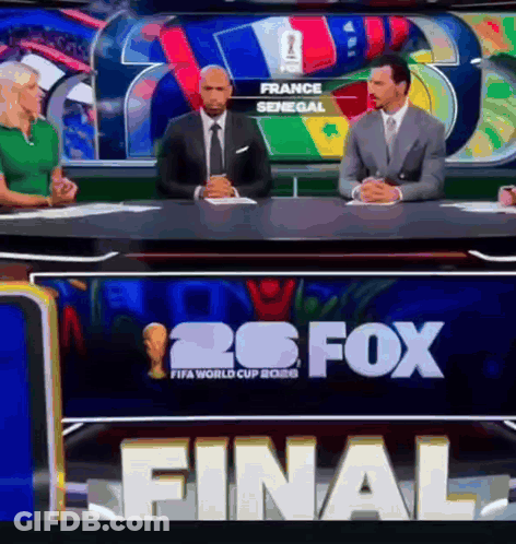 A Group Of People Sitting At A Table In Front Of A Sign That Says 26 Fox GIF