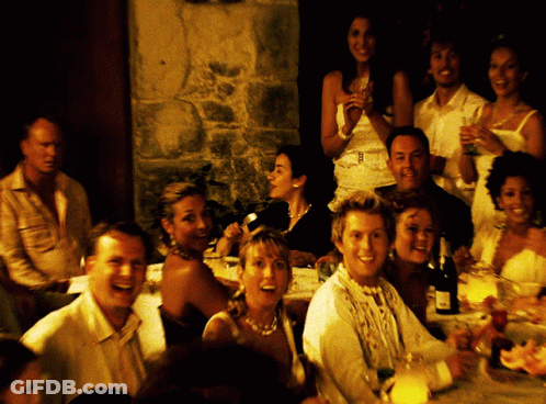 A Group Of People Sitting At A Table With A Bottle Of Wine On The Table GIF