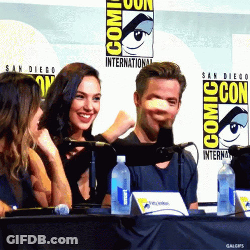 A Group Of People Sitting At A Table With A Comic Con Logo Behind Them GIF