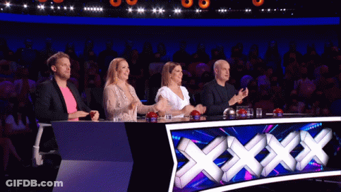 A Group Of People Sitting At A Table With A Sign That Says Xxx On It GIF