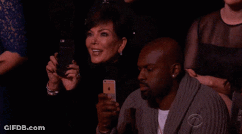 A Group Of People Sitting In A Dark Room With One Man Wearing A Sweater That Says Cbs On It GIF