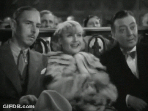 A Group Of People Sitting In A Theater Watching A Movie GIF