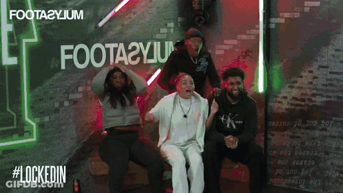 A Group Of People Sitting In Front Of A Sign That Says Foota2yjm GIF
