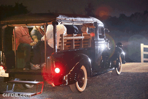 A Group Of People Sitting In The Back Of A Truck GIF