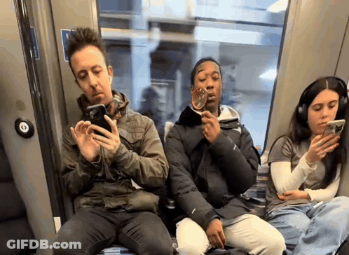 A Group Of People Sitting On A Bus Looking At Their Cell Phones GIF