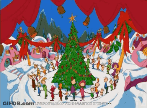 A Group Of People Standing Around A Christmas Tree GIF