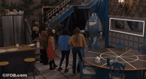 A Group Of People Standing Around A Round Table With A Robot On It GIF