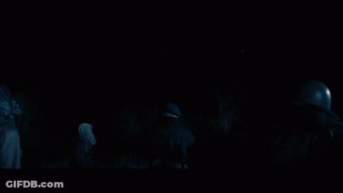 A Group Of People Standing In A Dark Room Looking At Something GIF