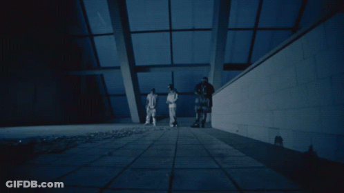 A Group Of People Standing In A Dark Room With A Blue Sky In The Background GIF
