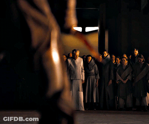 A Group Of People Standing In A Dark Room With A Man Holding A Sword GIF