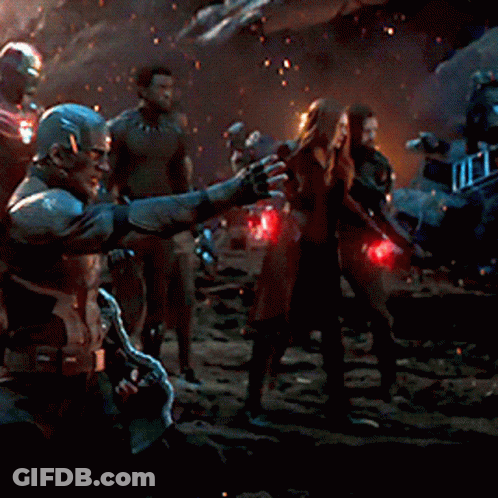 A Group Of People Standing In A Dark Room With A Man Pointing At Something GIF