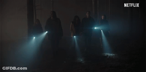 A Group Of People Standing In A Dark Room With A Netflix Logo In The Background GIF