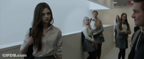 A Group Of People Standing In A Hallway With A Sign That Says Exit On It GIF