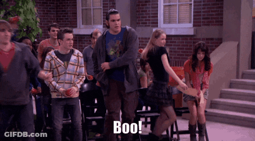 A Group Of People Standing In Front Of A Brick Building With The Word Boo Written On The Bottom GIF